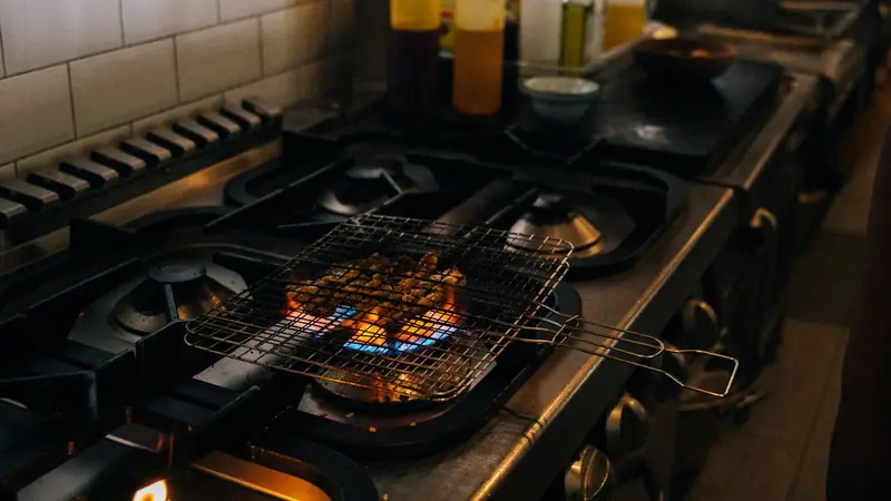 A commercial kitchen with gas flames on the grill