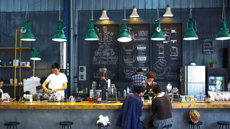 A busy café with staff behind the counter and customers ordering under warm pendant lights