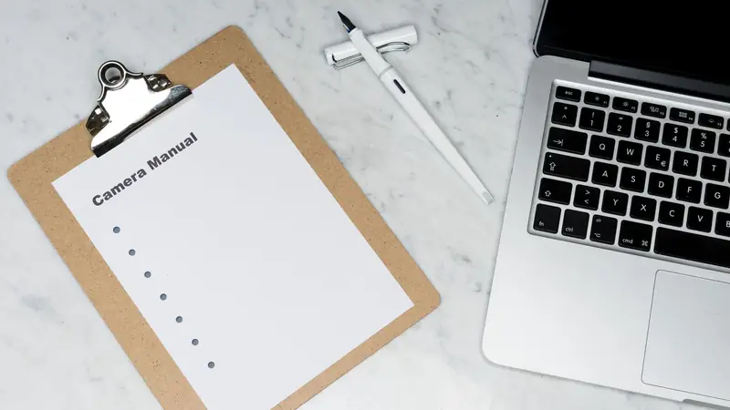 A laptop, clipboard and pen on a desk