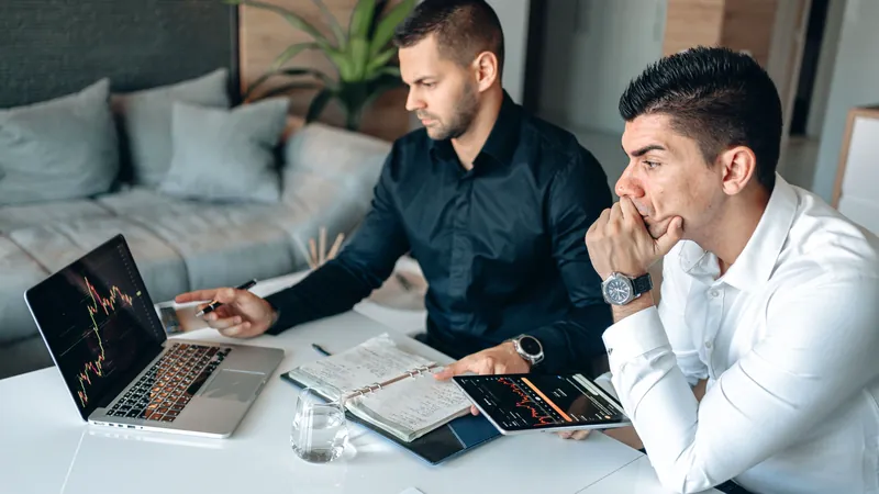 Two professionals reviewing figures on a laptop
