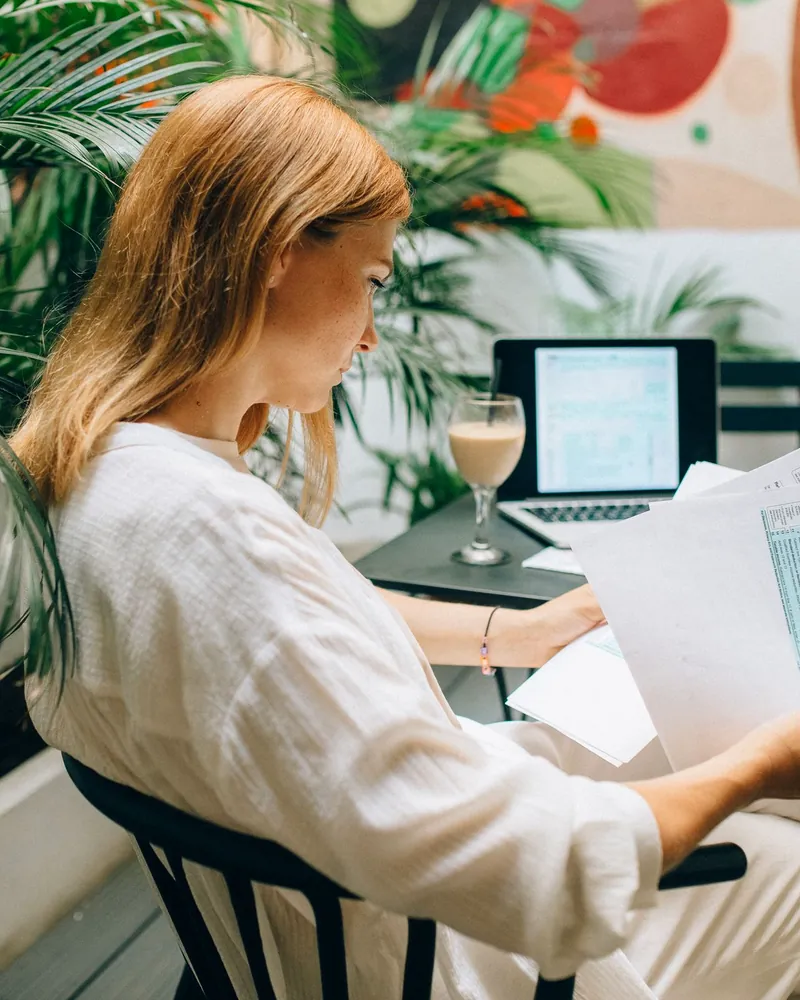 A business owner reviewing her bills at a bright desk with a laptop