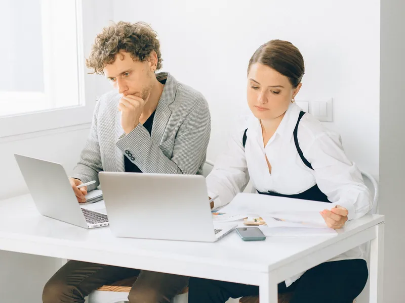 Two colleagues working through figures on their laptops